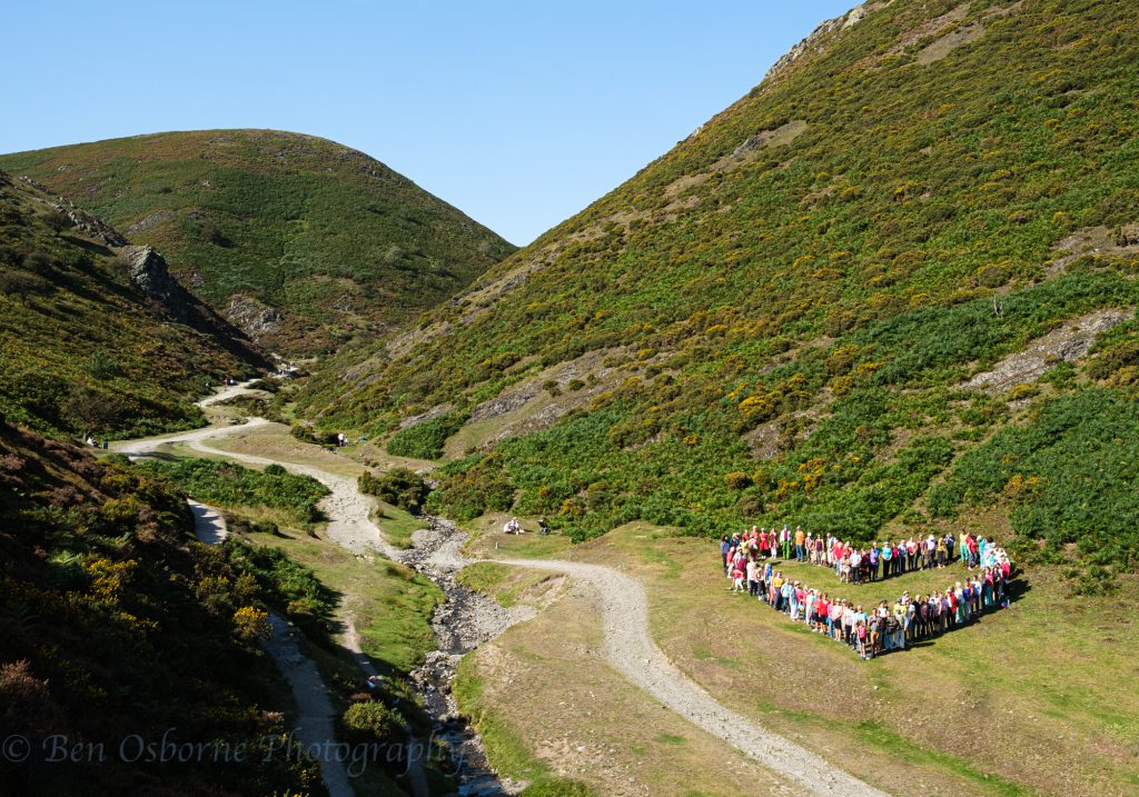 An image of people from Shropshire creating a heart formation in Carding Mill Valley in the heart of the Shropshire Hill Area of Outstanding Natural Beauty.