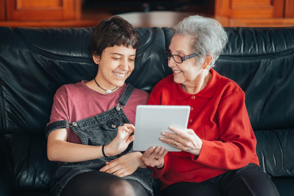 An image on a Granddaughter teaching her grandmother how to use a tablet and develop digital skills.