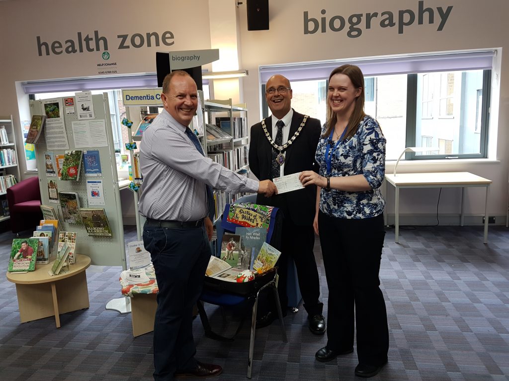 An image of a cheque presentation at Oswestry Library which will help resource further dementia support. 