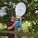 Recipient of alternative broadband solution in rural Shropshire in front of green trees on a sunny day with their wireless broadband service.