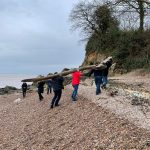 An image of Elvis the wooden Eel being carried from the beach by its finders