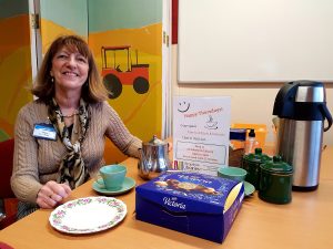 A woman sitting at a table with tea and biscuits