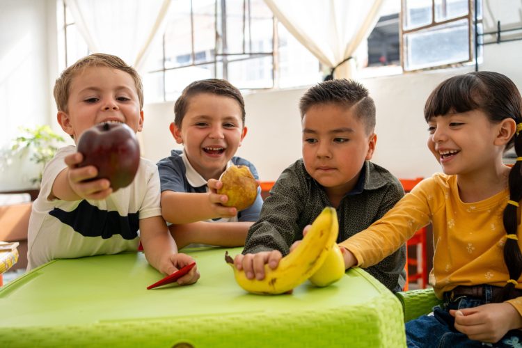 Smiling kindergarten kids show off their fruits in preschool class. A fun and colorful moment that highlights healthy habits and food learning through play.