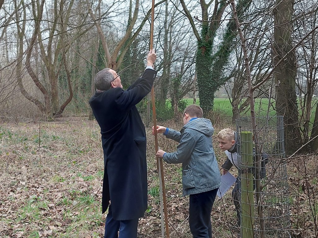 Holocaust Memorial Day 2022 - Tony Parsons, a local Shropshire Councillor for Bayston Hill, Column and Sutton, and two children measuring the tree at Mereside Primary School