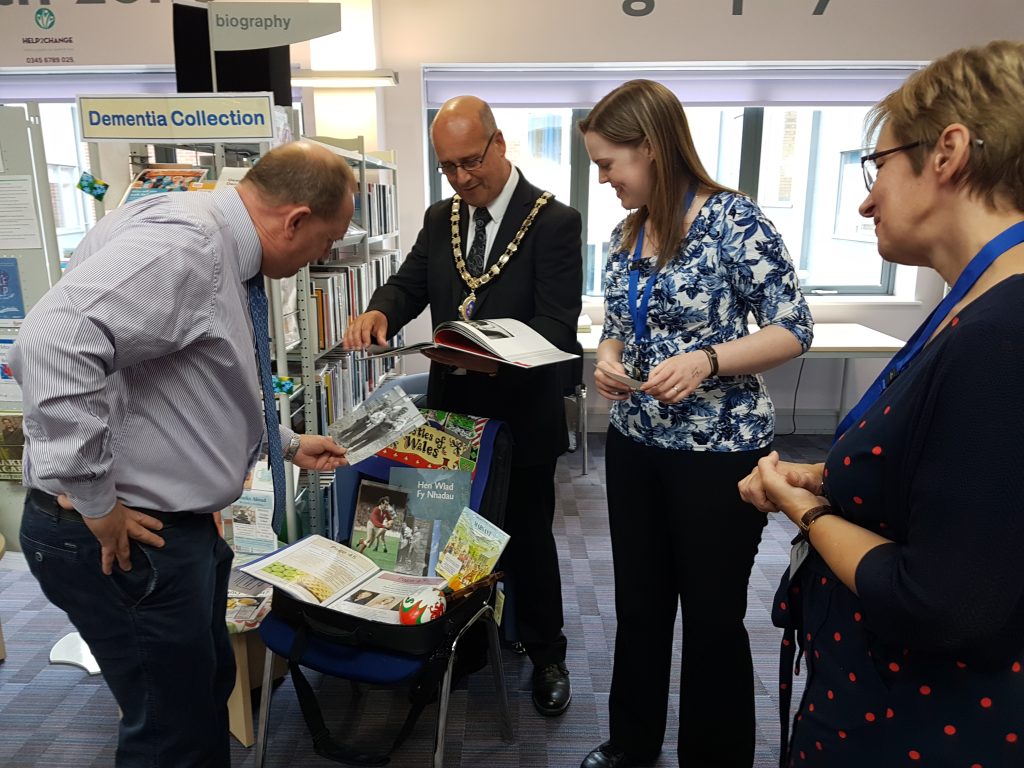 An image of people inspecting the shared memory bags at Oswestry Library that support people living with dementia and their carers.