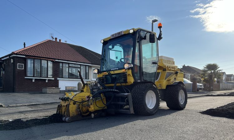 A Multihog repairing a road in a residential street, with a bungalow in the background