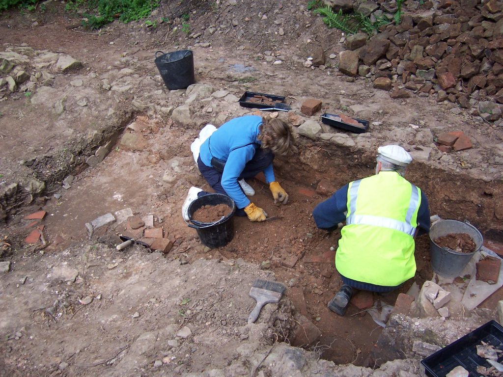 An image of two volunteers working on a previous archaeology project.