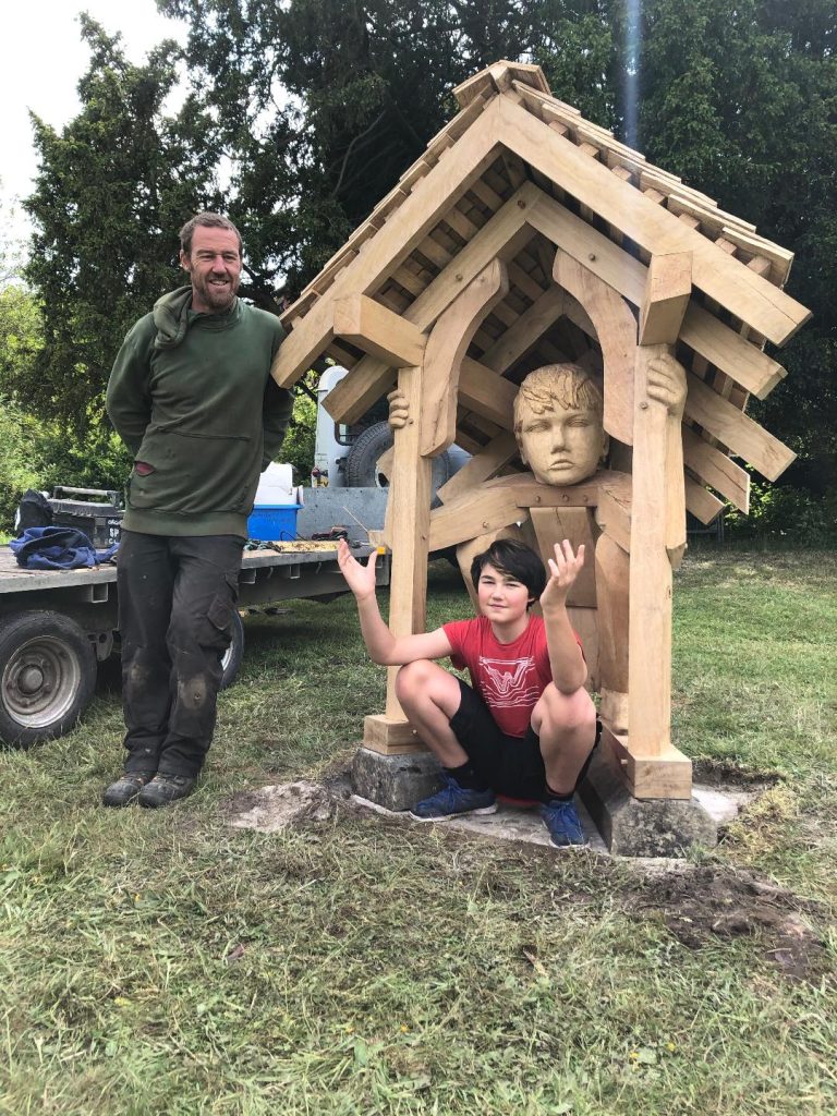 John Merrill with his sculpture Refuge. The refugee child was modelled by his son, Josef, aged 12