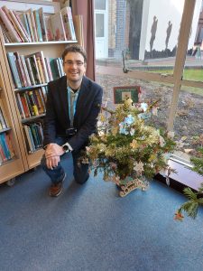 A man beside a small decorated Christmas tree