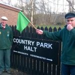 Two volunteers with leaflets and a train flag, at Severn Valley Country Park halt on the Severn Valley Railway.