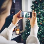 A lady filming a Christmas tree with a mobile phone