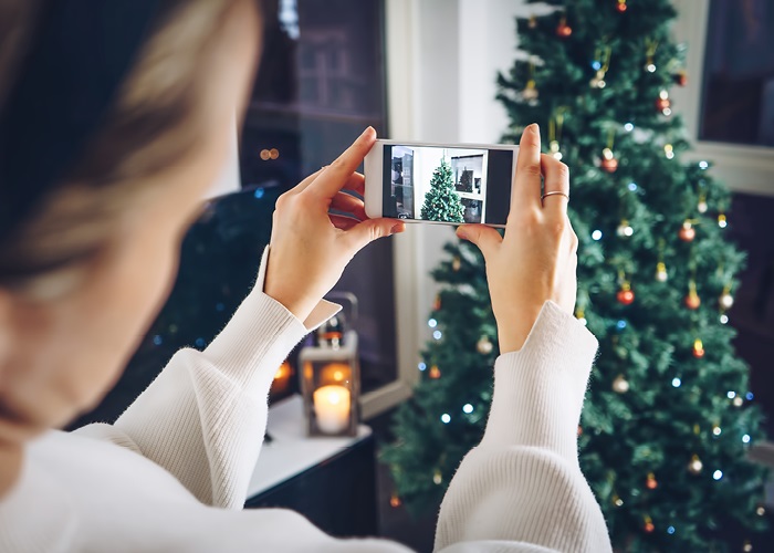 A lady filming a Christmas tree with a mobile phone