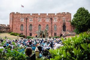 Shewsbury Castle with a crowd of people observing outdoor theatre