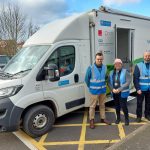 A health checks van and three outreach officers wearing blue jackets