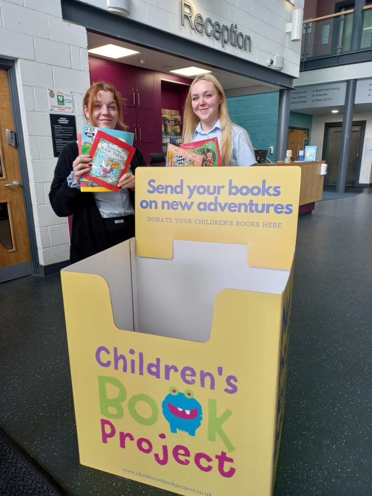 One of the book bins, plus 2 staff members holding books