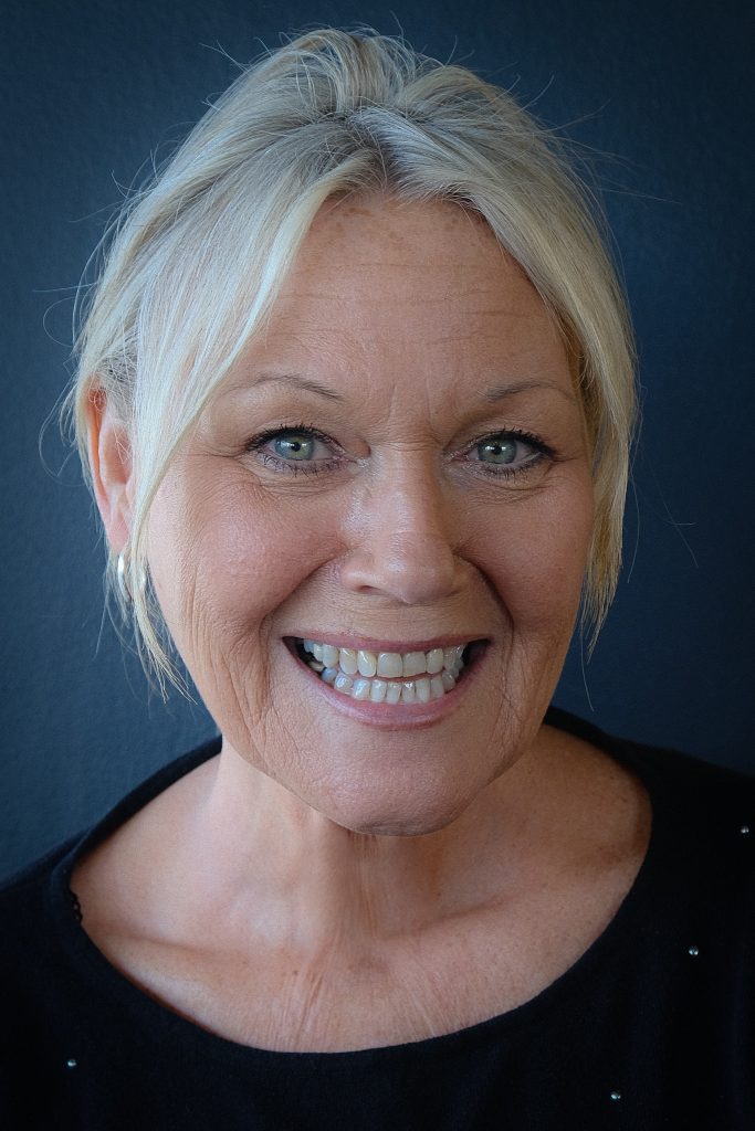  A blue background with a blonde woman who is smiling