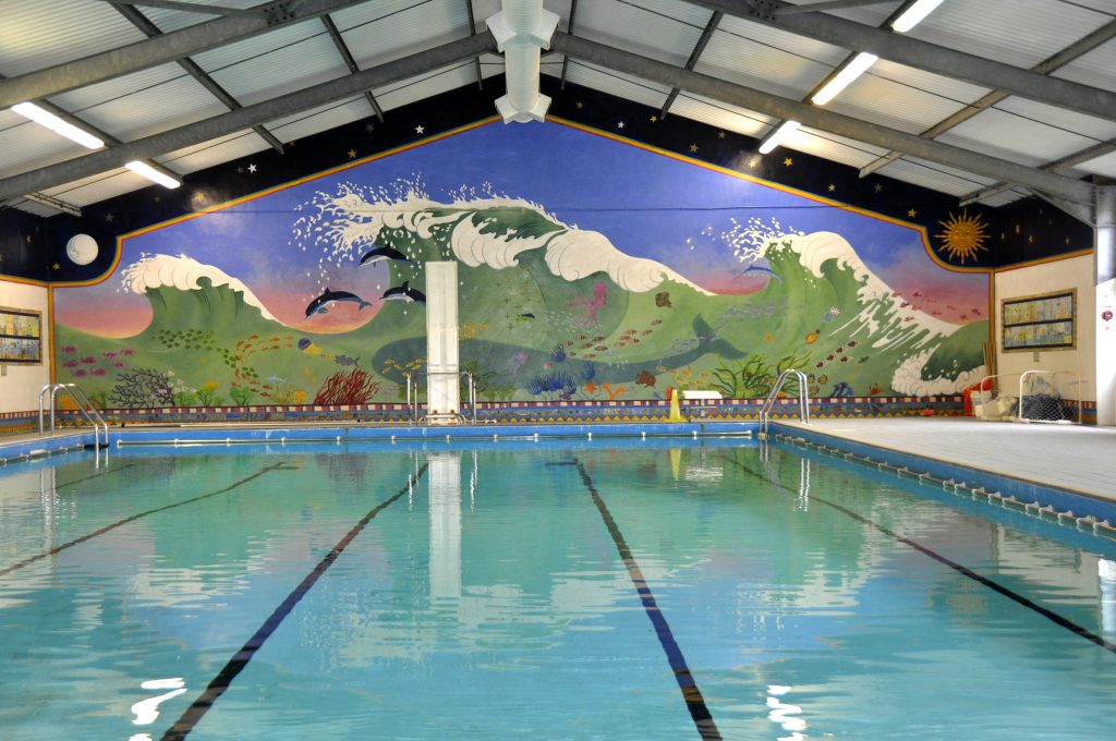 A swimming pool with a colourful wall in the background