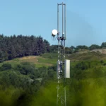 A Vodaphone mast against blue sky and countryside