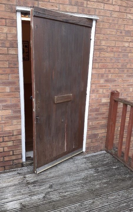 The old fire exit door, complete with letterbox, and corner of the unsafe rotten decking.