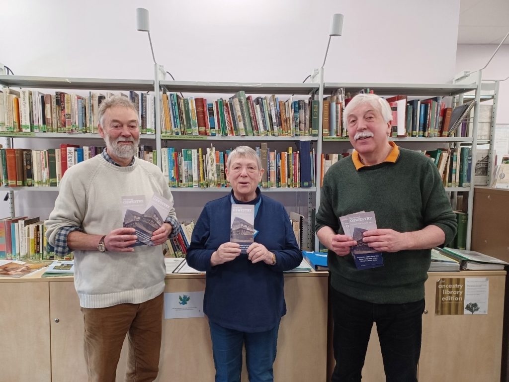3 people holding leaflets in a library