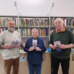 3 people holding leaflets in a library