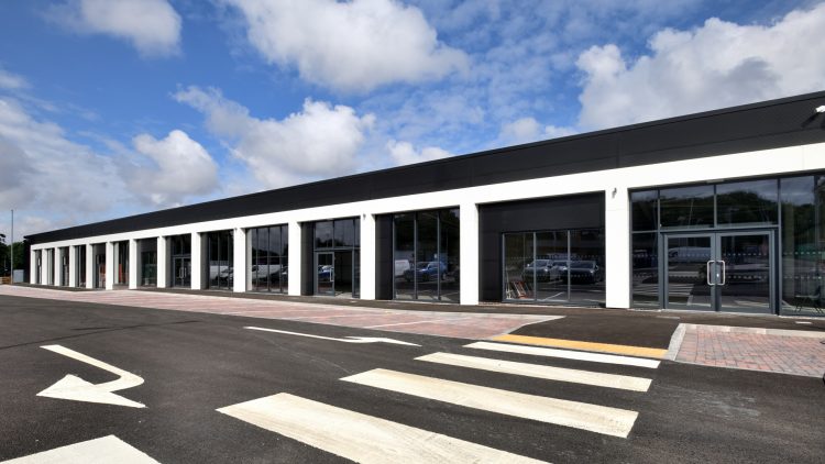 A row of empty retail units with a road and zebra crossing in the foreground