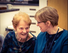 An image of a librarian from Shropshire Libraries with a recipient of one of the Shared Memory Bags which support Shropshire residents with memory loss and their supporters.