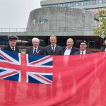 People with a flag for Merchant Navy Day 2023.