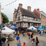 Oswestry town centre showing pedestrians walking round market stalls on the pavements