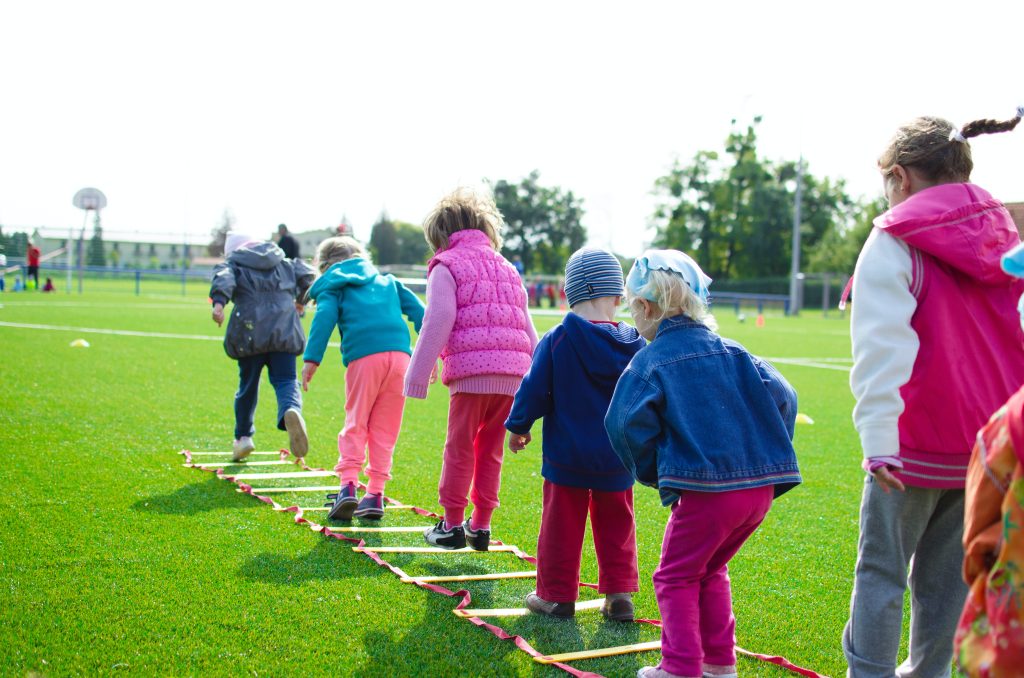 Children playing in a field with PE equipment