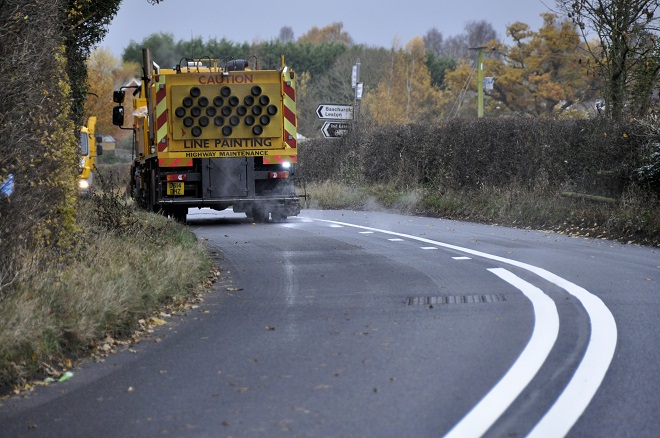 A line painting vehicle on a newly-resurfaced road