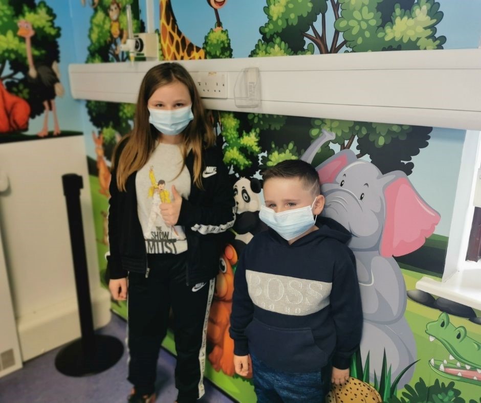 Pictured are Emmy Jones, aged 11, and her younger brother, Jack, 6, from Ellesmere, stood in front of the jungle-themed mural at the RJAH Vaccination Centre.