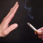 An outstretched hand in a 'stop' gesture in front of a cigarette