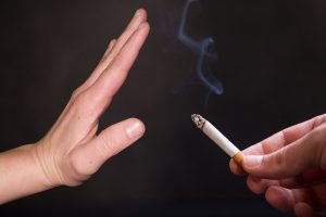 An outstretched hand in a 'stop' gesture in front of a cigarette