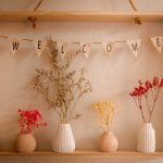 Some fabric bunting with the letters WELCOME and dried flowers in vases underneath