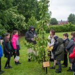 An image of Imam Sohayb Peerbhai with children from Woodside Primary School in Oswestry gathered around a cherry tree commemorating Ann Frank and the remembering the victims of the Holocaust.